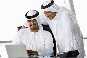Two businessmen in office with laptop smiling (high key/selective focus)