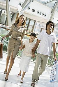 Family walking in mall holding hands and smiling (selective focus)
