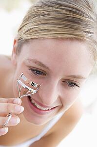 Woman with eyelash curler smiling