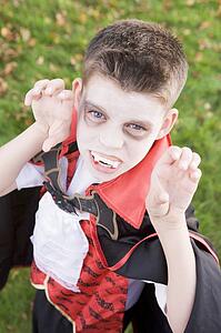 Young boy outdoors wearing vampire costume on Halloween