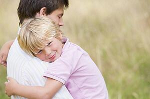 Father holding son outdoors smiling