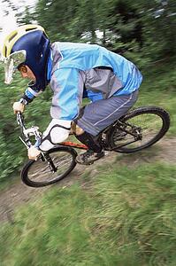 Man outdoors on trails riding bicycle (selective focus)