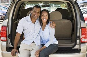 Couple sitting in back of van smiling