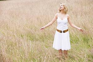 Woman standing outdoors holding grass smiling