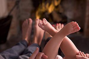 Family of feet warming at a fireplace