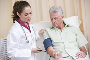 Doctor checking man's blood pressure in exam room