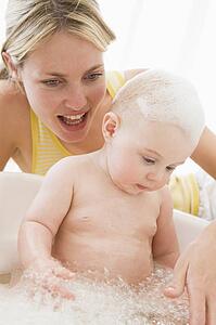 Mother giving baby bubble bath smiling