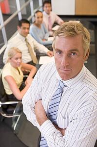 Businessman with four businesspeople at boardroom table in background