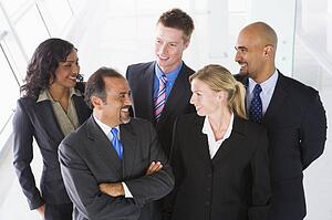 Group of co-workers standing in office space smiling (high key)