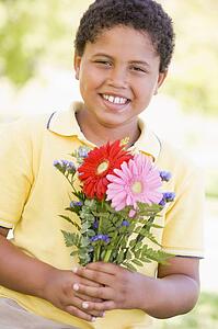Young boy holding flowers and smiling