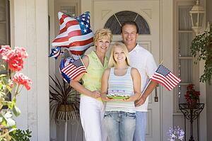 Family at front door on fourth of July with flags and cookies smiling