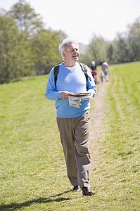Man walking outdoors holding map smiling with people in background