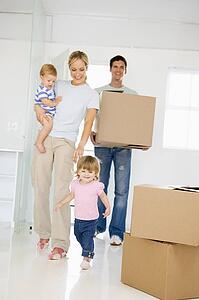 Family with box moving into new home smiling