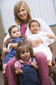 Doctor sitting with three IVF children smiling