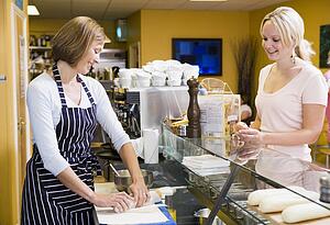 Woman standing at counter in restaurant serving customer smiling