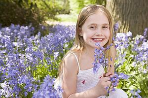 Young girl outdoors holding flowers smiling