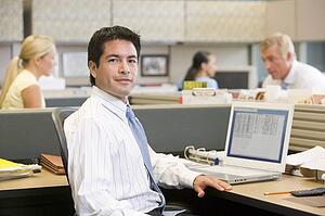 Businessman in cubicle with laptop