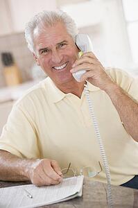 Man in kitchen on telephone smiling