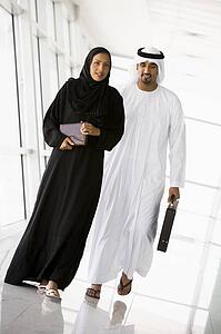 Two businesspeople walking in a corridor and smiling (high key/selective focus)