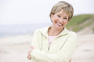 Woman at the beach with arms crossed smiling