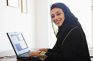 Woman in office with laptop smiling (high key/selective focus)