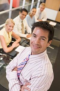 Businessman with four businesspeople at boardroom table in background