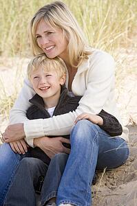 Mother and son sitting on beach smiling