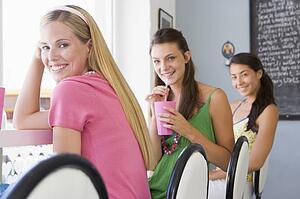 Three young women having a cold drink in a cafeteria