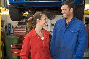 Two mechanics standing in garage smiling