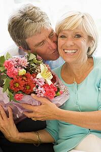 Husband giving wife flowers kissing and smiling