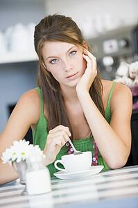 Young woman sitting at a table drinking tea