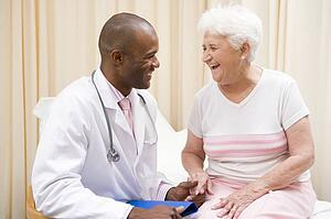 Doctor giving checkup to woman in exam room smiling