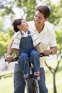 Man and young boy on a bike outdoors smiling