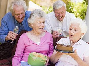Two couples on patio with cake and gift smiling