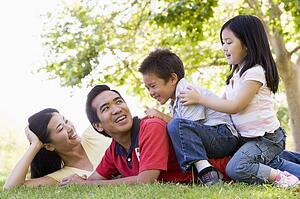 Family lying outdoors being playful and smiling