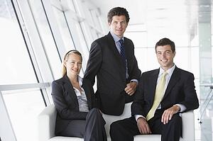 Three businesspeople sitting in office lobby smiling