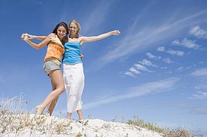 Two young women posing on a sand hill