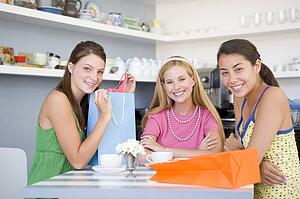 Three young woman sitting at a table taking a break from shopping
