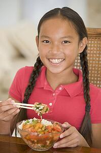 Young girl in dining room eating chinese food smiling