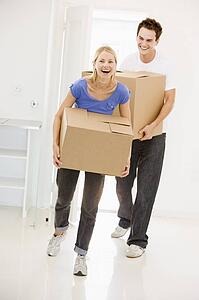 Couple with boxes moving into new home smiling