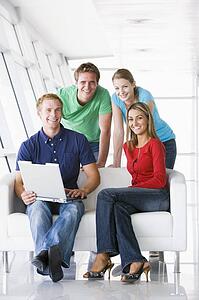 Four people in lobby with laptop smiling