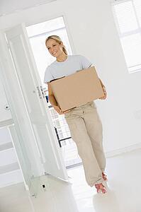 Woman with box moving into new home smiling