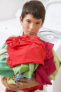 Young Boy Holding A Pile Of Laundry
