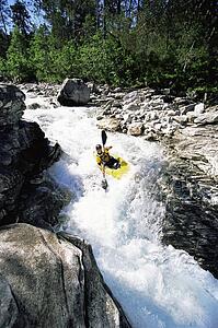 Kayaker in rapids going over waterfall
