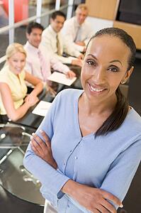 Businesswoman with four businesspeople at boardroom table in background
