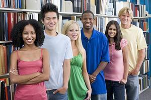 Six people in library standing by bookshelves