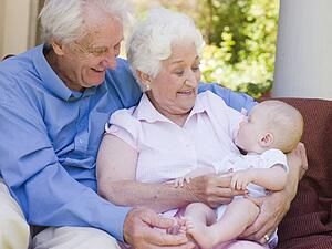 Grandparents outdoors on patio with baby smiling