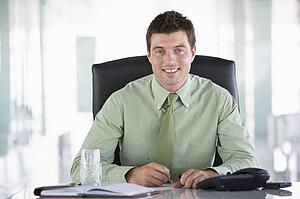 Businessman sitting in office with personal organizer smiling