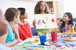 Student showing teacher and classmates her artwork (selective focus)