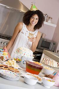 Woman at party holding drink standing by food table smiling